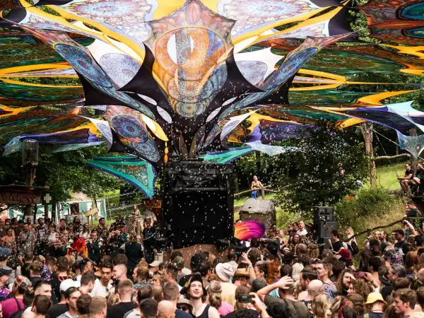 Bunte Stoffbahnen überspannen die Menge auf dem Wunderland Festival. Seifenblasen steigen auf, während die Besucher tanzen.