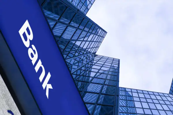 Niebieski szyld z napisem "Bank" na tle nowoczesnych, szklanych wieżowców. Czy to bank z 1600 roku?