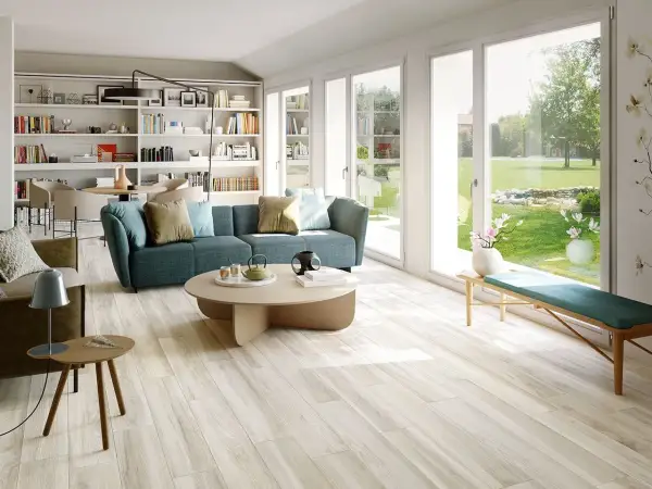 Soggiorno luminoso con divano blu e pavimento in gres porcellanato effetto legno, che mostra come rendere lucido il gres porcellanato effetto legno.