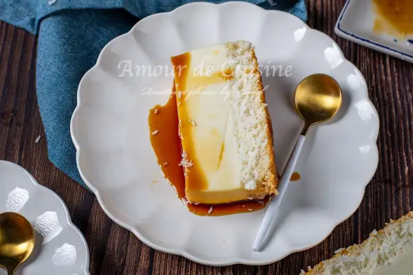 Tranche de flan coco antillais onctueux, nappé de caramel, avec une croûte de noix de coco râpée. Une cuillère dorée est posée à côté.