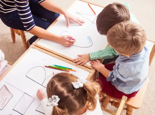 Kinder malen und lernen spielerisch im Kindergarten. Bunte Stifte und viel Kreativität bei den Sprachspielen.