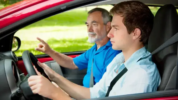 Joven conductor aprende a manejar con su instructor. ¡Con 17 años ya se puede sacar el carnet de conducir!
