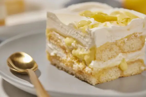 Ein Stück cremiges Lemon Tiramisu mit Löffel auf einem Teller.