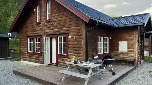 Mysig trästuga med grill och picknickbord på altanen, perfekt för en avkopplande vistelse på buskvallen inn.