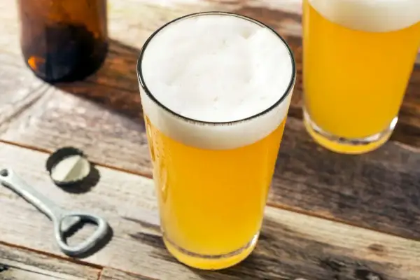 Bicchieri di birra dorata con schiuma bianca, su un tavolo di legno. La gradazione alcolica della birra è un dettaglio importante per gli amanti.