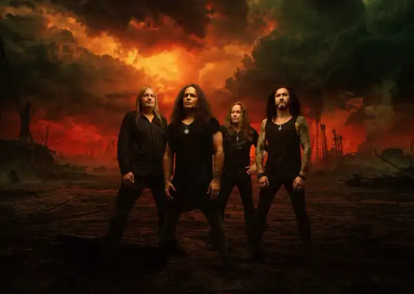 Los miembros de Kreator posan ante un cielo apocalíptico de fuego y humo.