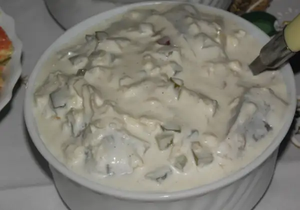 Pyszne śledzie w śmietanie, z kawałkami ogórka i cebuli, gotowe do podania.