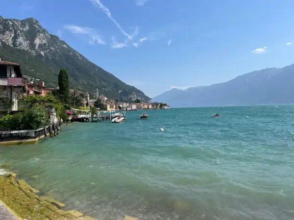 Vista sul lago con montagne sullo sfondo, barche e case colorate. Un vero gargnano geheimtipp.