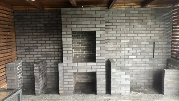 Nowy, murowany prosty grill z cegły czeka na pierwsze rozpalenie. Wygodny, z miejscem na drewno i akcesoria.