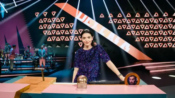 Eine Frau in Glitzerkleid steht im Rampenlicht, während eine Band im Hintergrund spielt. Wer stiehlt mir die Show?