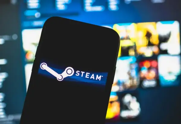 Smartfon z logo Steam na ekranie, w tle rozmyte okładki gier. Czekam na oczekujące środki Steam.