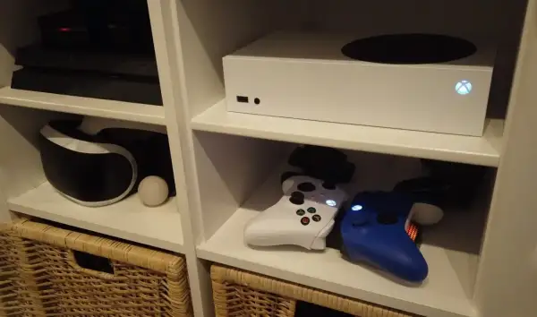 Biały Xbox Series S, który wyszedł w 2020 roku, stoi na półce obok konsoli PlayStation i kontrolerów.