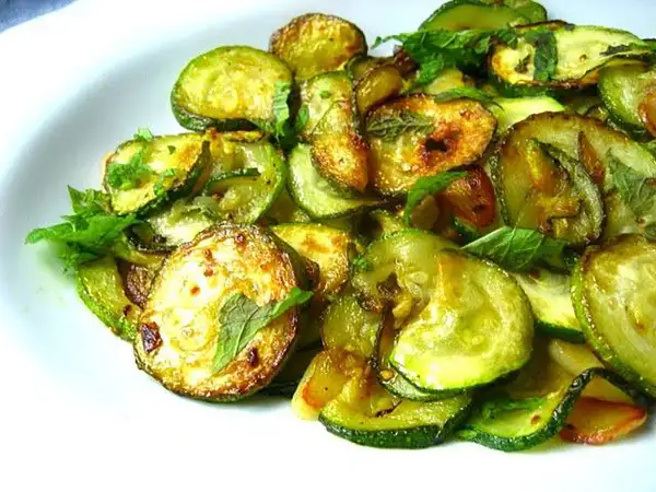 Zucchine alla scapece ricetta napoletana: fette di zucchine fritte e marinate con menta fresca, un contorno saporito e profumato.
