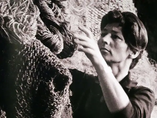 Magdalena Abakanowicz dotyka swojej monumentalnej rzeźby z włókien, tworząc dzieło sztuki.