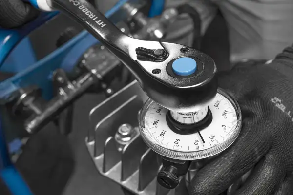 Mano enguantada ajustando una llave dinamométrica con dial para medir el par de apriete. Aprende como usar llave dinamometrica.