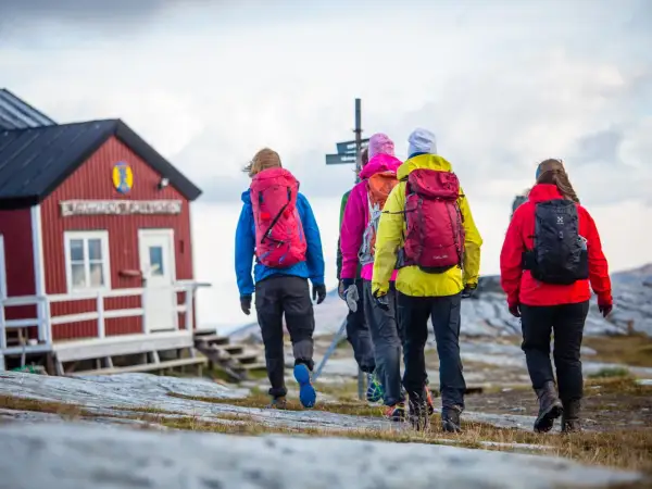Vandringsgrupp närmar sig STF Sylarnas fjällstation. Vackert höstlandskap med molnig himmel.