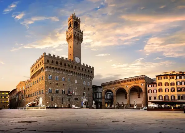 Il maestoso Palazzo Vecchio domina Piazza della Signoria, con la sua torre imponente che svetta nel cielo al tramonto.