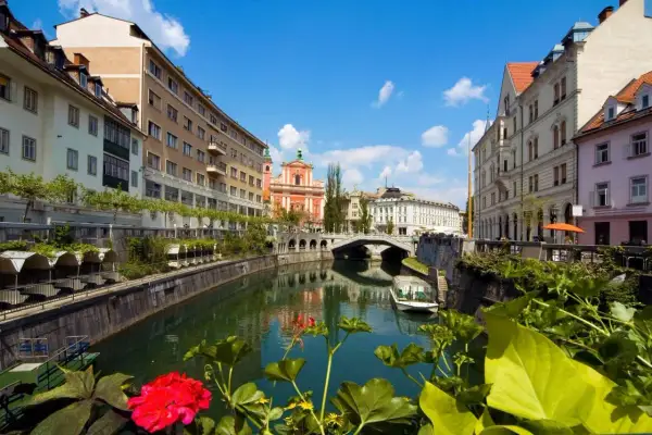 Urokliwy widok na rzekę w Lublanie, stolicy Słowenii, z mostem i kolorową architekturą.