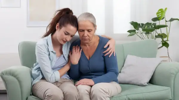 Giovane donna conforta madre anziana, un abbraccio di sostegno per il permesso per lutto suocero.