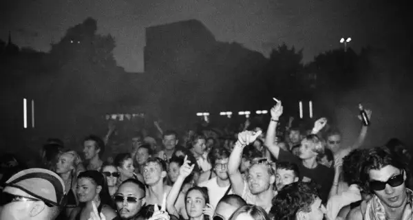Folla in delirio a un concerto, con mani alzate e luci soffuse. Marco festa dj fa ballare tutti.