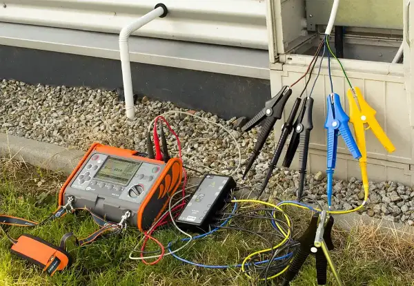 Miernik testuje rezystancję izolacji przewodów podłączonych do skrzynki elektrycznej.