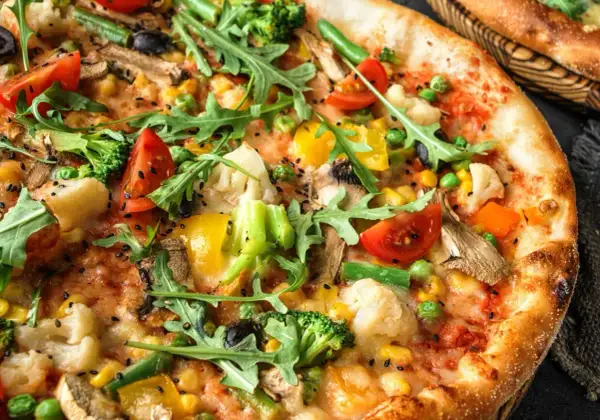Apetyczna pizza bez mięsa z brokułami, pomidorkami, kukurydzą i rukolą.
