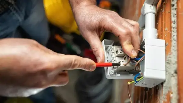Elettricista collega cavi a una presa, mostrando le differenze tra i tipi di connessione.