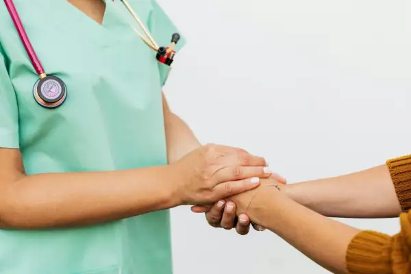 Un infermiere rassicura un paziente, superando la paura dei medici con un gesto di conforto.