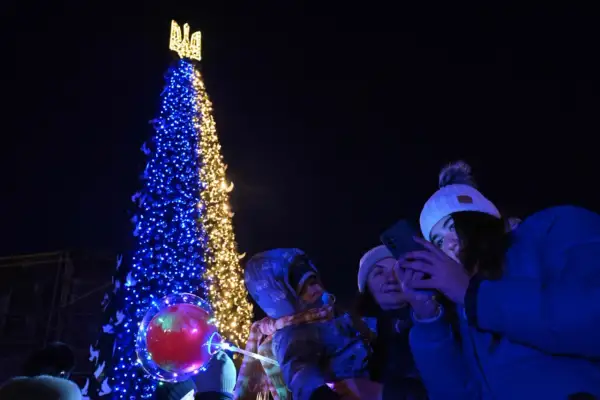 Choinka ozdobiona w barwach Ukrainy, ludzie robiący zdjęcia telefonami.