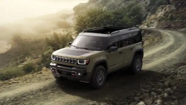 Jeep Recon in verde militare affronta un sentiero sterrato in montagna, pronto per ogni avventura.