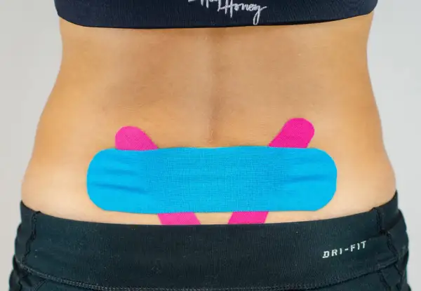 LWS tapen: Blaues und pinkes Kinesio-Tape stützt den unteren Rücken für mehr Stabilität und Schmerzlinderung.
