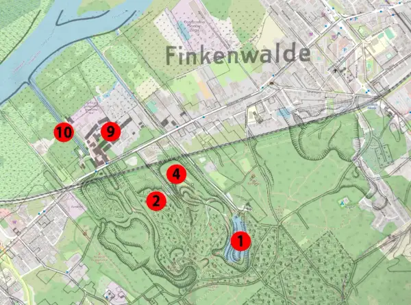 Mapa Finkenwalde z zaznaczonymi punktami. Wzgórza, parki i budynki, a pośrodku malownicze szmaragdowe oczko wodne.