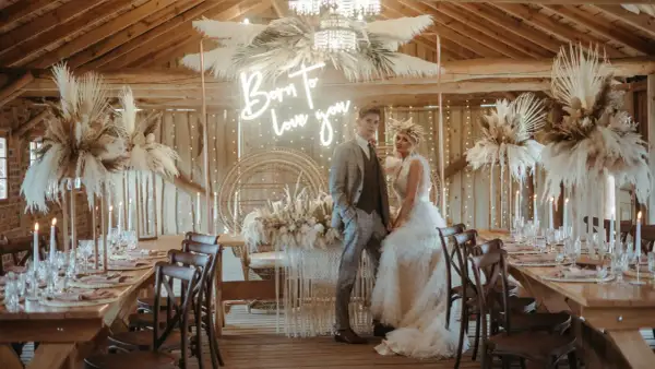 Eleganckie wesele w stodole: boho dekoracje z traw pampasowych, neon "Born to love you" i para młoda.