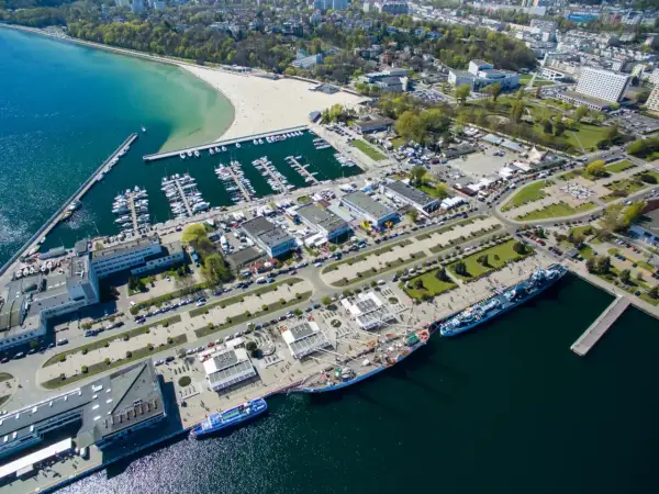 Gdynia co zobaczyć: malownicza plaża, pełny jachtów port, statki i miejska panorama. Idealne miejsce na spacer i podziwianie widoków.