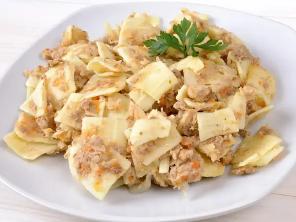 Pyszne lazanki z mielonym mięsem i warzywami, udekorowane gałązką natki pietruszki.