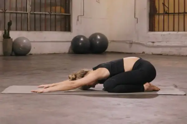 Mujer en postura de niño, una de las posturas de yoga para estirar la espalda.