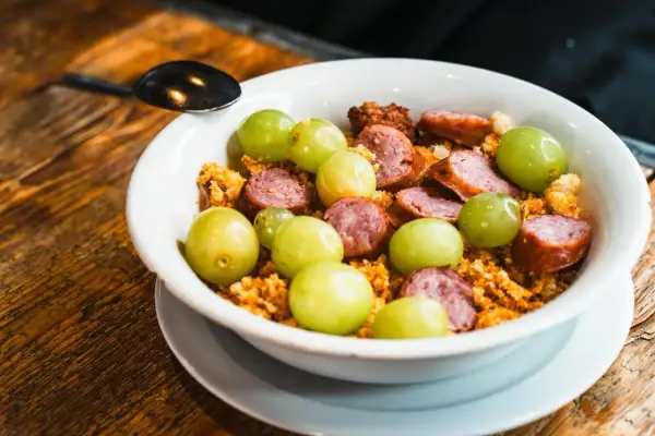 Un plato con uvas verdes, chorizo en rodajas y migas crujientes, un sabor que recuerda a el tubo zaragoza.
