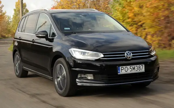 Czarny Volkswagen Touran 1.9 TDI 105 KM szarpie przy przyspieszaniu, jadąc po drodze wśród jesiennych drzew.