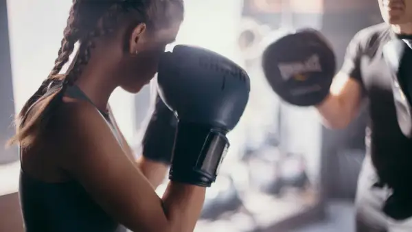 A boxer trains with her coach, practicing punches. This image shows the dedication needed to learn how to be a boxing coach.