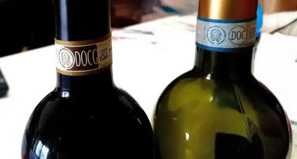 Dwie butelki włoskich win DOCG, czerwonego i białego, gotowe do degustacji.