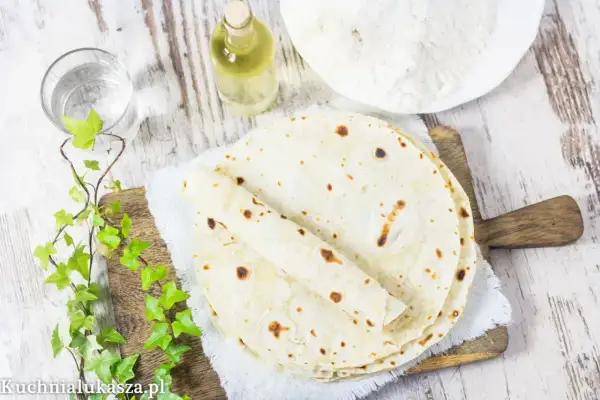 Domowy tortilla przepis: świeżo upieczone placki, mąka, olej i woda na drewnianej desce.