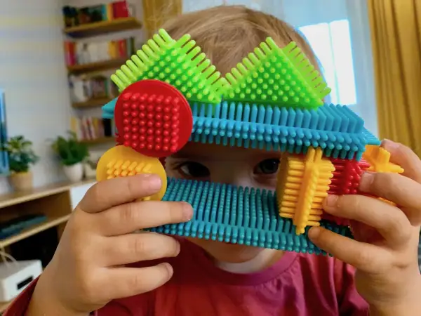 Dziecko bawi się kolorowymi klockami, które mogą być idealnym prezentem pod choinkę dla 2 latka.