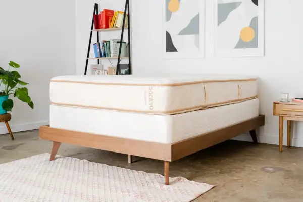 A Saatva mattress on a wooden bed frame, perfect for answering "cual es el mejor colchon para dolor de espalda.