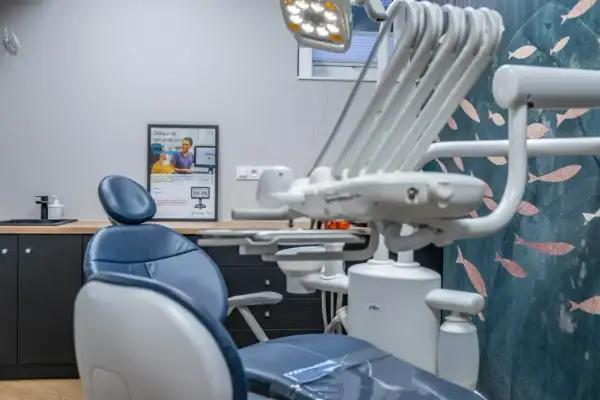 Nowoczesny gabinet stomatologiczny, gotowy na sanację zębów. Wygodny fotel, lampa i estetyczna tapeta tworzą przyjazną atmosferę.