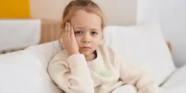 Ein trauriges Kind mit Kopfschmerzen, das sich im Bett ausruht. Vielleicht ist es ein Zeichen für schnelles Wachstum.