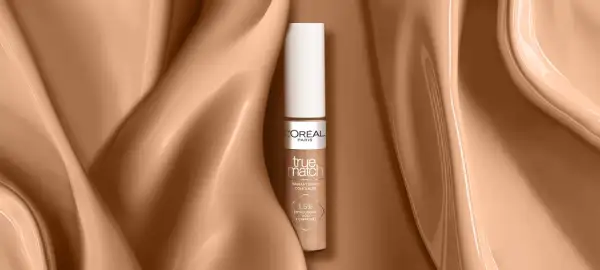 Un correcteur jaune L'Oréal True Match, présenté sur un fond satiné couleur peau.