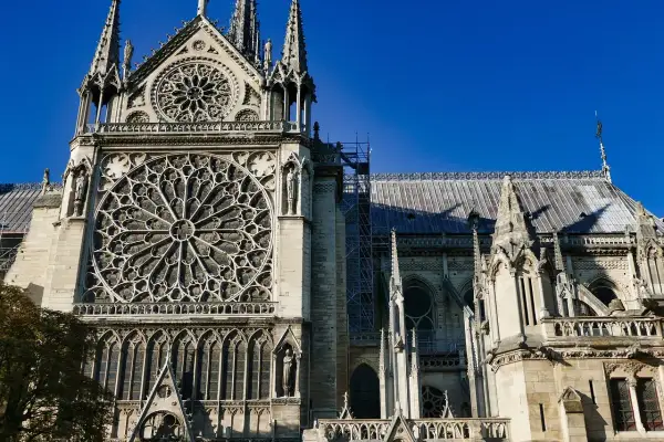 Majestatyczna katedra Notre Dame w Paryżu z imponującą rozetą i gotyckimi detalami, na tle błękitnego nieba.