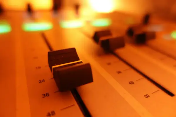 Suwaki miksera audio, oświetlone ciepłym, pomarańczowym światłem. To miejsce, gdzie rodzi się dźwięk.
