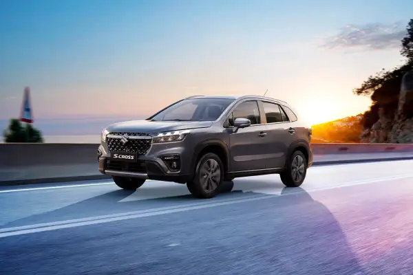 Grå Suzuki S-Cross kör längs en väg vid solnedgången. Inga problem här, bara en vacker resa.