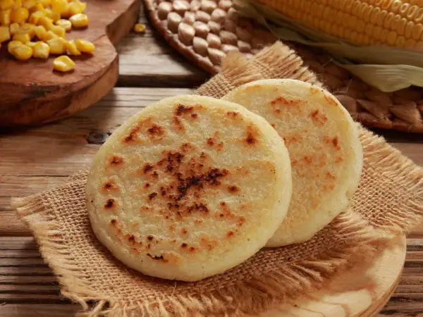 Deux arepas dorées, garnies de maïs, sur une toile de jute. Un délice à déguster !